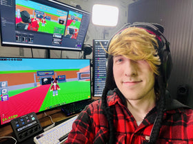 Roblox streamer KreekCraft at his gaming desk with monitors showing gameplay, used as contextual creator imagery for The Hollow coverage